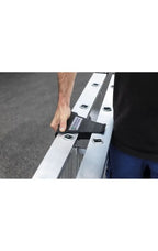 Schwarzer stoffriemen mit etikett sichert zwei silberne aluminiumleiterabschnitte der munk stufen-stehleiter einseitig begehbar mit clip-step r13