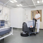 Grau-schwarze nilfisk scheuersaugmaschine ba611 mit langem griff und ladegerät für den einsatz im klinik- und gewerbebereich