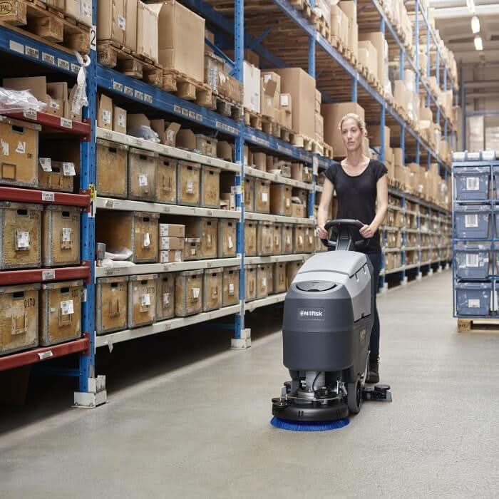 Graue und schwarze nilfisk scheuersaugmaschine sc401 e kabelversion mit blauem bürstenkopf für lagerböden