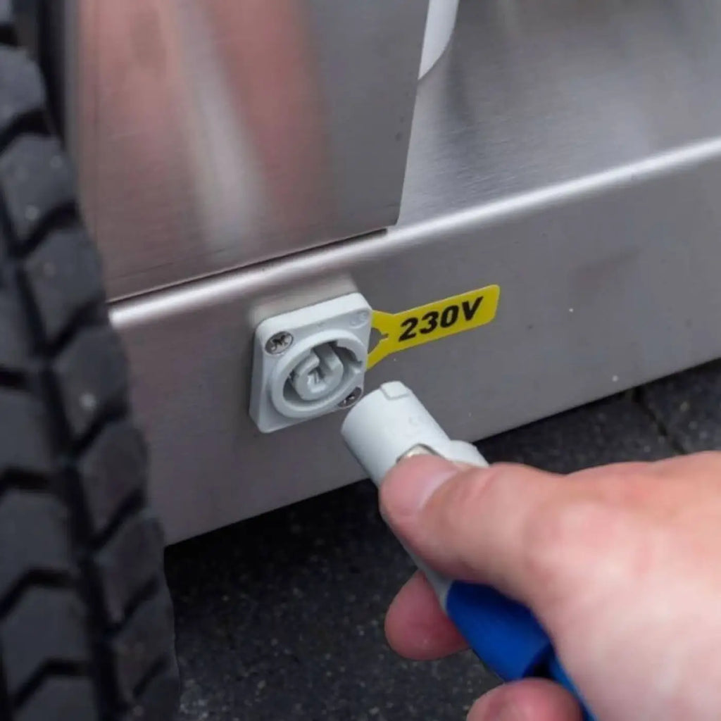 Weißer kunststoffstecker mit blauem griff wird in steckdose eines edelstahlgeräts des osmobil pro x eingeführt
