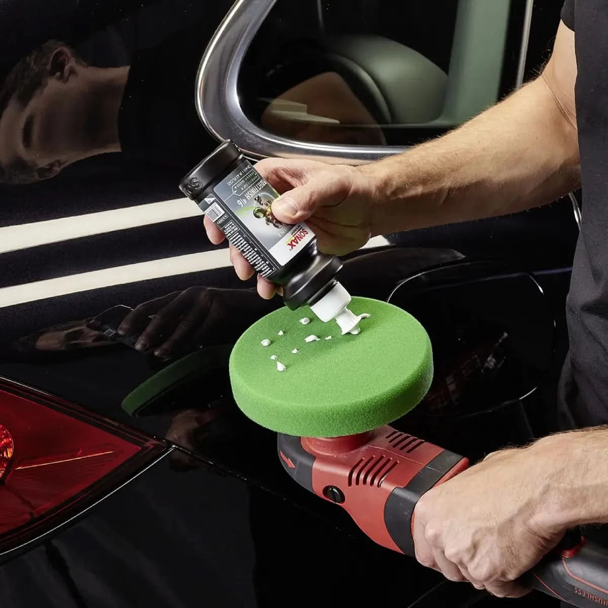 Schwarze meguiars ultimate polish flasche mit weißer applikatorspitze über grünem schaumstoffpad am polierer